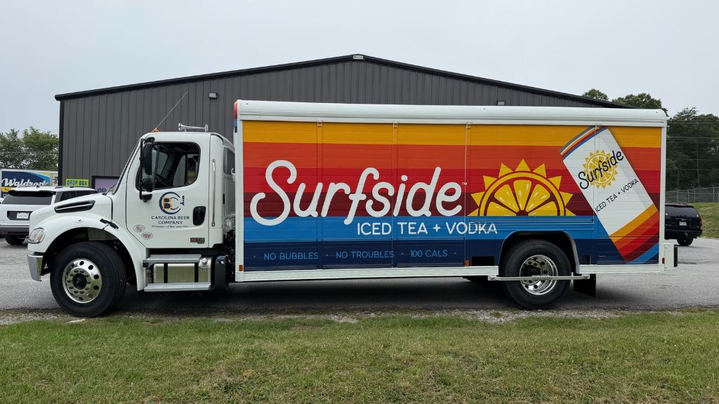 Box truck with custom vehicle wrap displaying business branding and graphics.